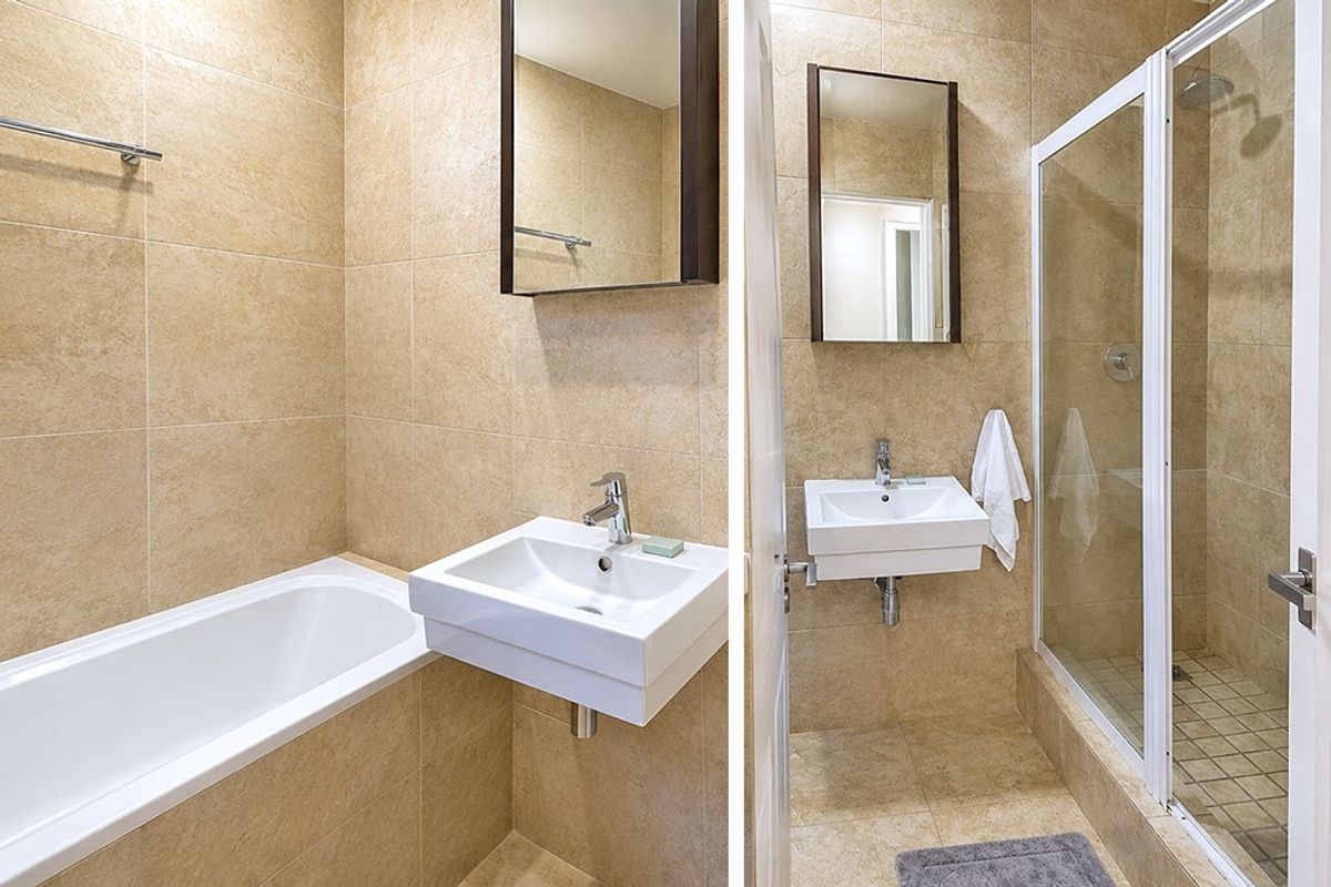 A clean, tiled bathroom featuring a wall-mounted basin, a bathtub, and a separate glass-enclosed shower area.