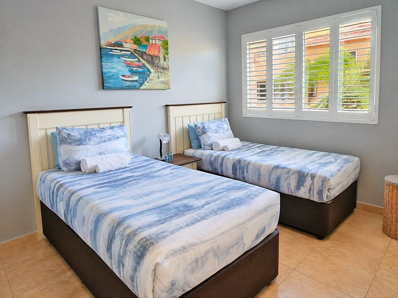 A well-maintained bedroom featuring tiled flooring and white plantation shutters, providing a bright and comfortable living space.