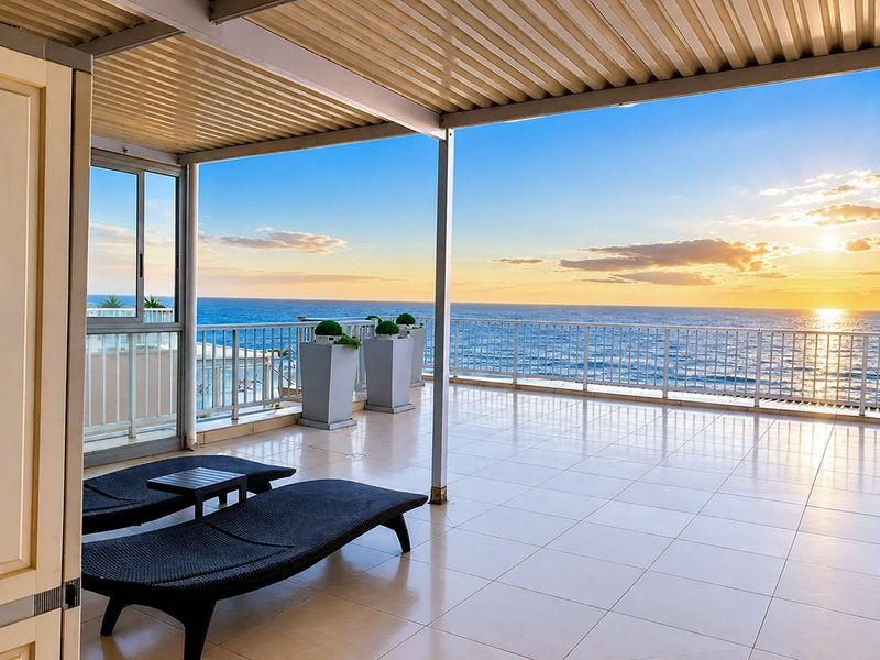 Spacious covered balcony featuring tiled flooring, metal railings, and expansive ocean views, perfect for outdoor relaxation.