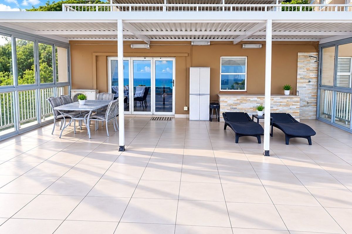 Spacious covered patio featuring tiled flooring, stone-clad accents, and large sliding glass doors, offering a seamless transition to outdoor living.