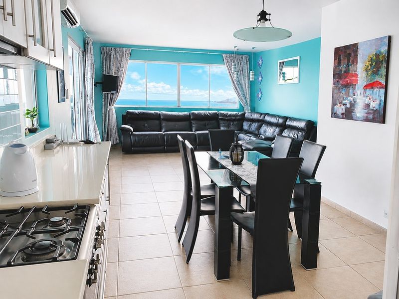 Open-plan living, dining, and kitchen area featuring tiled floors, modern cabinetry, gas cooktop, and expansive ocean views through large windows.