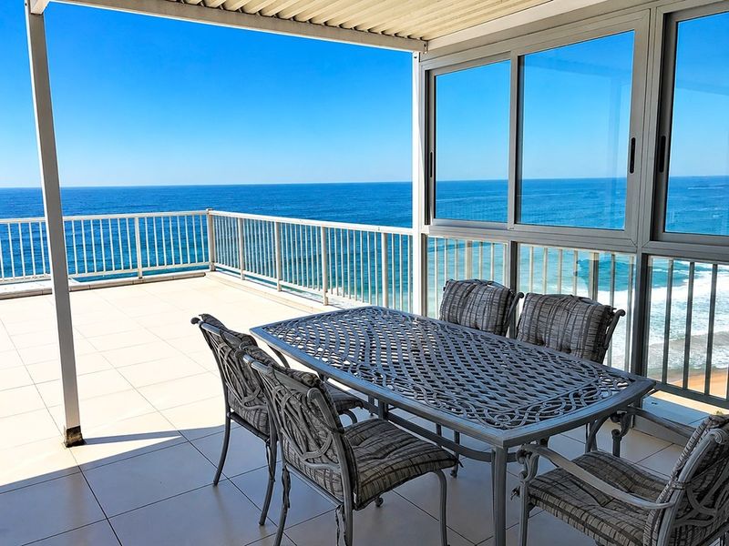 Spacious covered balcony featuring tiled flooring, metal balustrades, and expansive ocean views, providing an ideal outdoor entertainment space.