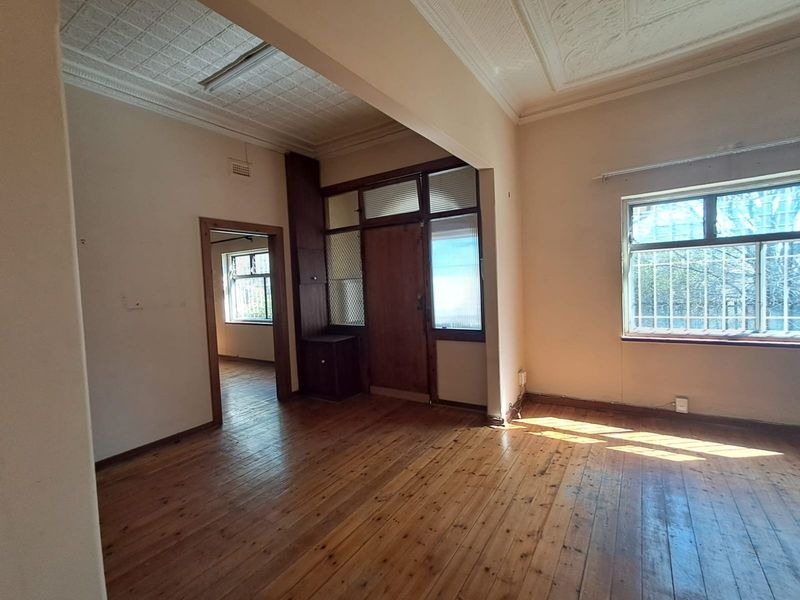 Spacious living area featuring original timber flooring, pressed metal ceilings, and built-in cabinetry, offering a blank canvas for renovation.