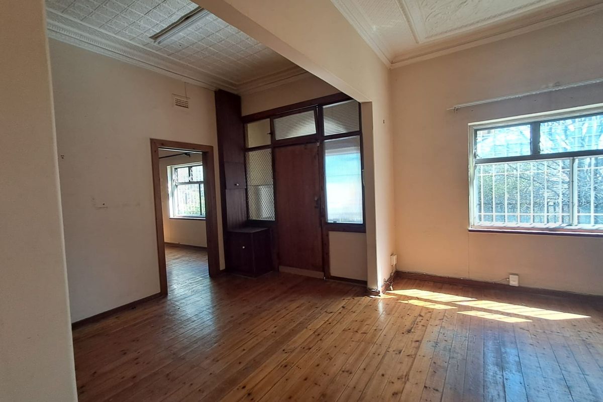Spacious living area featuring original timber flooring, pressed metal ceilings, and built-in cabinetry, offering a blank canvas for renovation.
