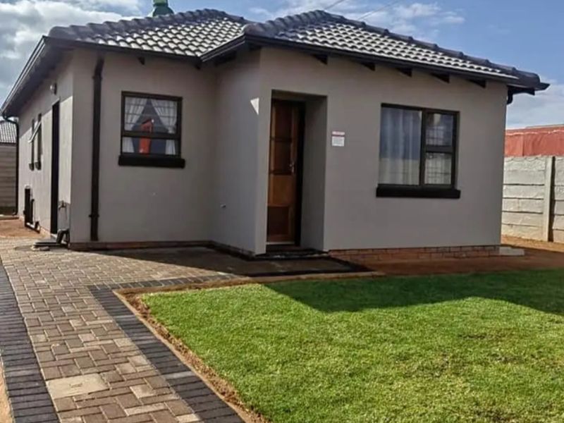 A well-maintained single-story residential home featuring a tiled roof, paved walkway, and a neat front lawn with secure boundary walling.