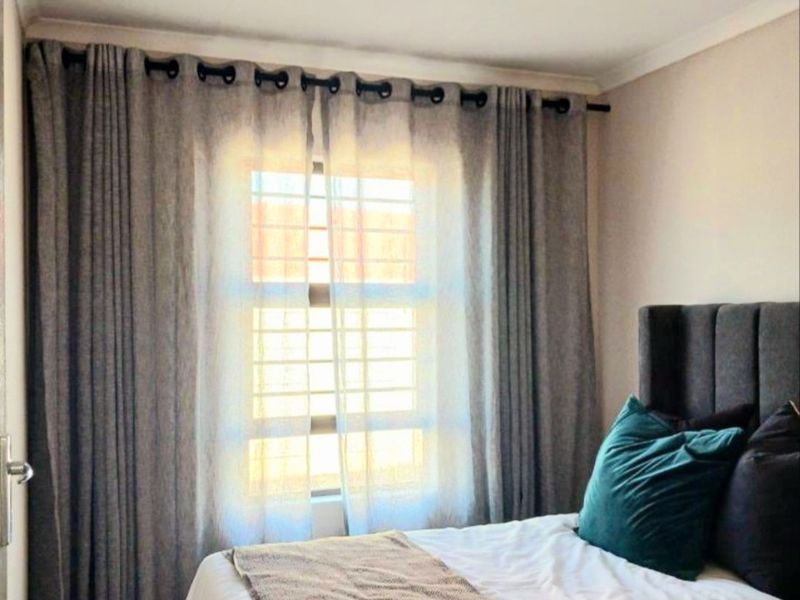 A well-maintained bedroom featuring a window with security bars and neutral wall finishes.