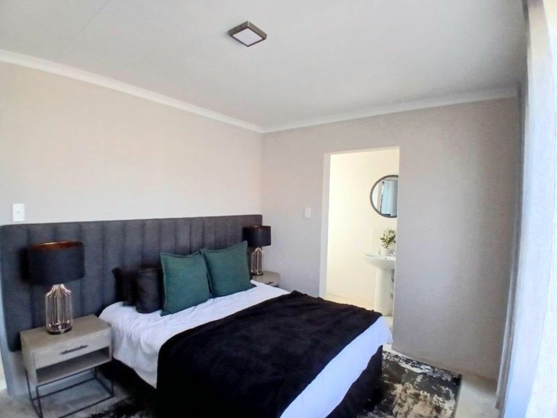 A well-maintained bedroom featuring a modern upholstered headboard, neutral wall tones, and direct access to an en-suite bathroom.
