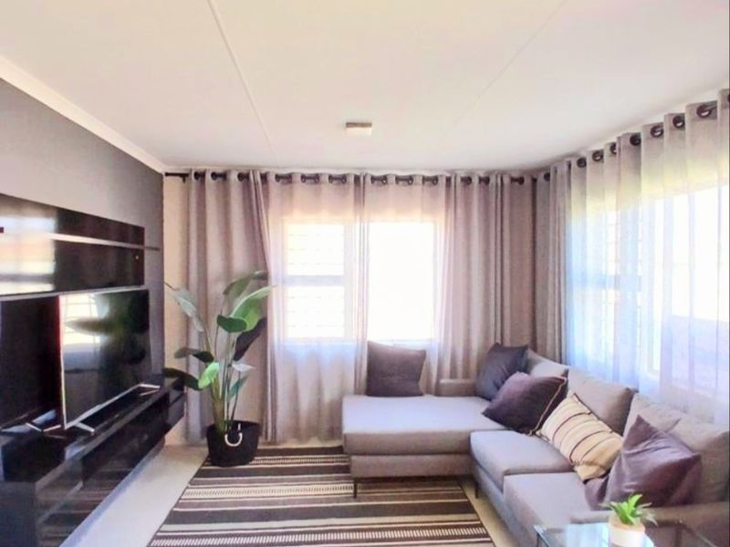 A well-maintained living room featuring a sleek, wall-mounted media console and large windows that provide ample natural light.