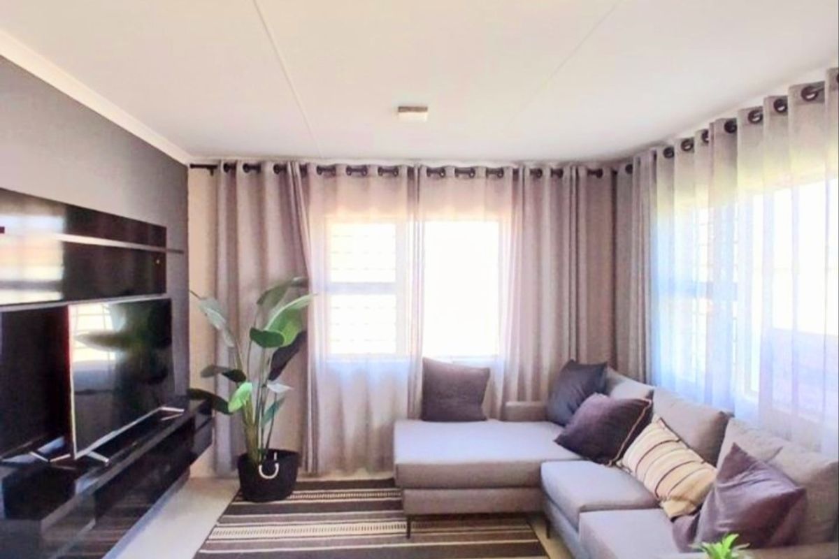A well-maintained living room featuring a sleek, wall-mounted media console and large windows that provide ample natural light.