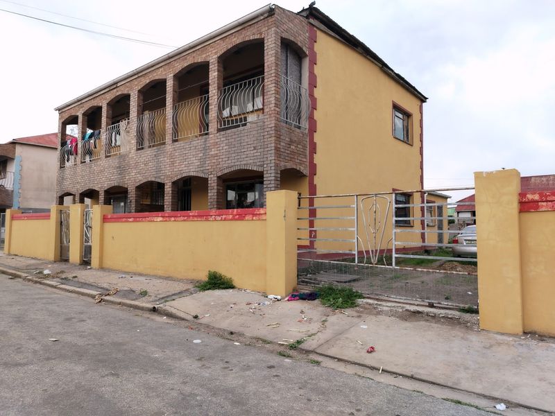 Two-story commercial building featuring a brick facade, upper-level balconies with wrought iron railings, and a gated perimeter wall.