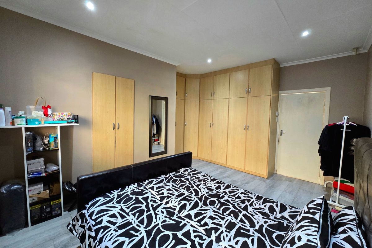 A bedroom featuring extensive built-in wooden cabinetry, tiled flooring, and recessed ceiling lighting, providing ample storage space.