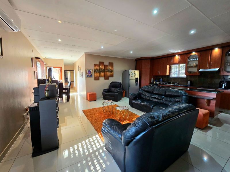 Spacious open-plan living area featuring tiled floors, recessed lighting, and a functional kitchen with built-in wooden cabinetry and an integrated extractor fan.