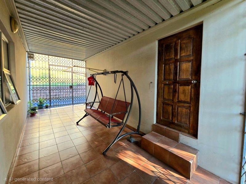 A covered outdoor patio area featuring tiled flooring, a timber entrance door with steps, and a secure metal gate enclosure.