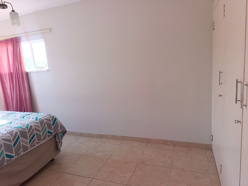 A bedroom featuring tiled flooring and built-in cupboards, providing functional storage space.