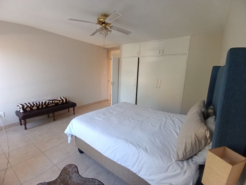 A bedroom featuring tiled flooring, a ceiling fan, and ample built-in cupboard storage space.
