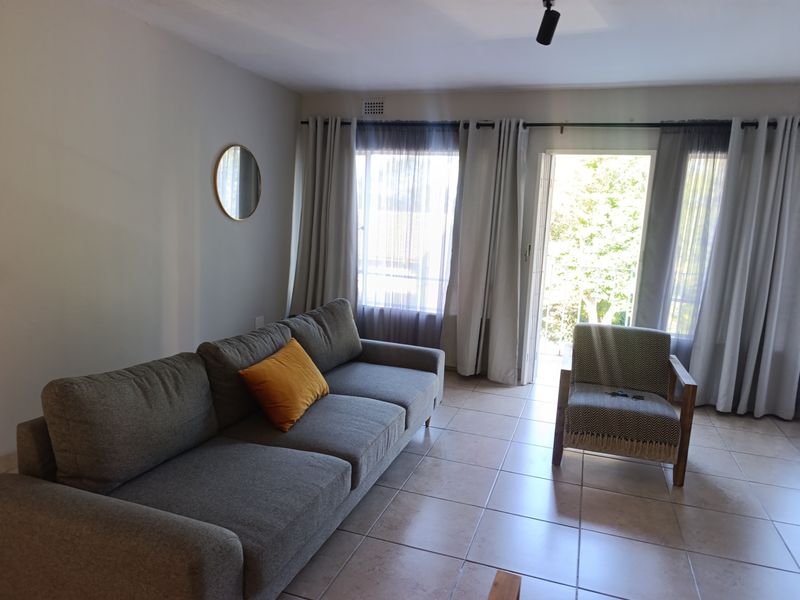 A bright living room featuring tiled flooring and a sliding door providing access to an outdoor area.