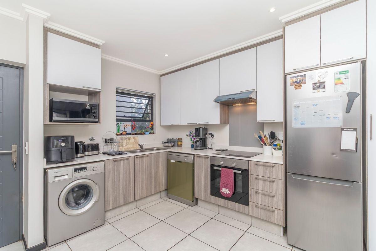 Modern kitchen featuring light wood-grain cabinetry, stone-look countertops, integrated appliances, and tiled flooring, offering a clean and functional workspace.