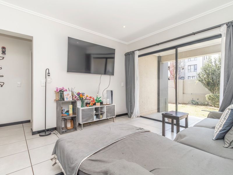 A bright living room featuring tiled flooring, modern cornicing, and large sliding glass doors that provide direct access to the outdoor patio area.