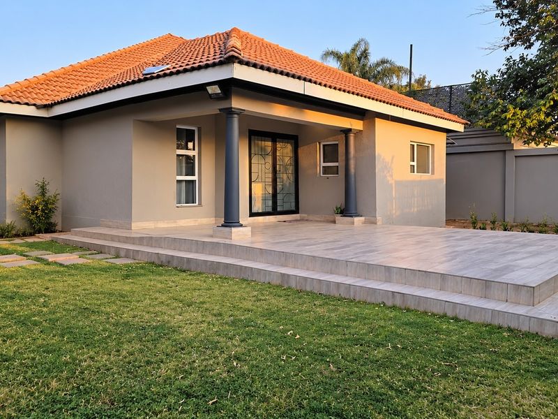 A well-maintained cottage exterior featuring a spacious tiled patio, terracotta roof tiles, and secure sliding door access, set within a neat garden.