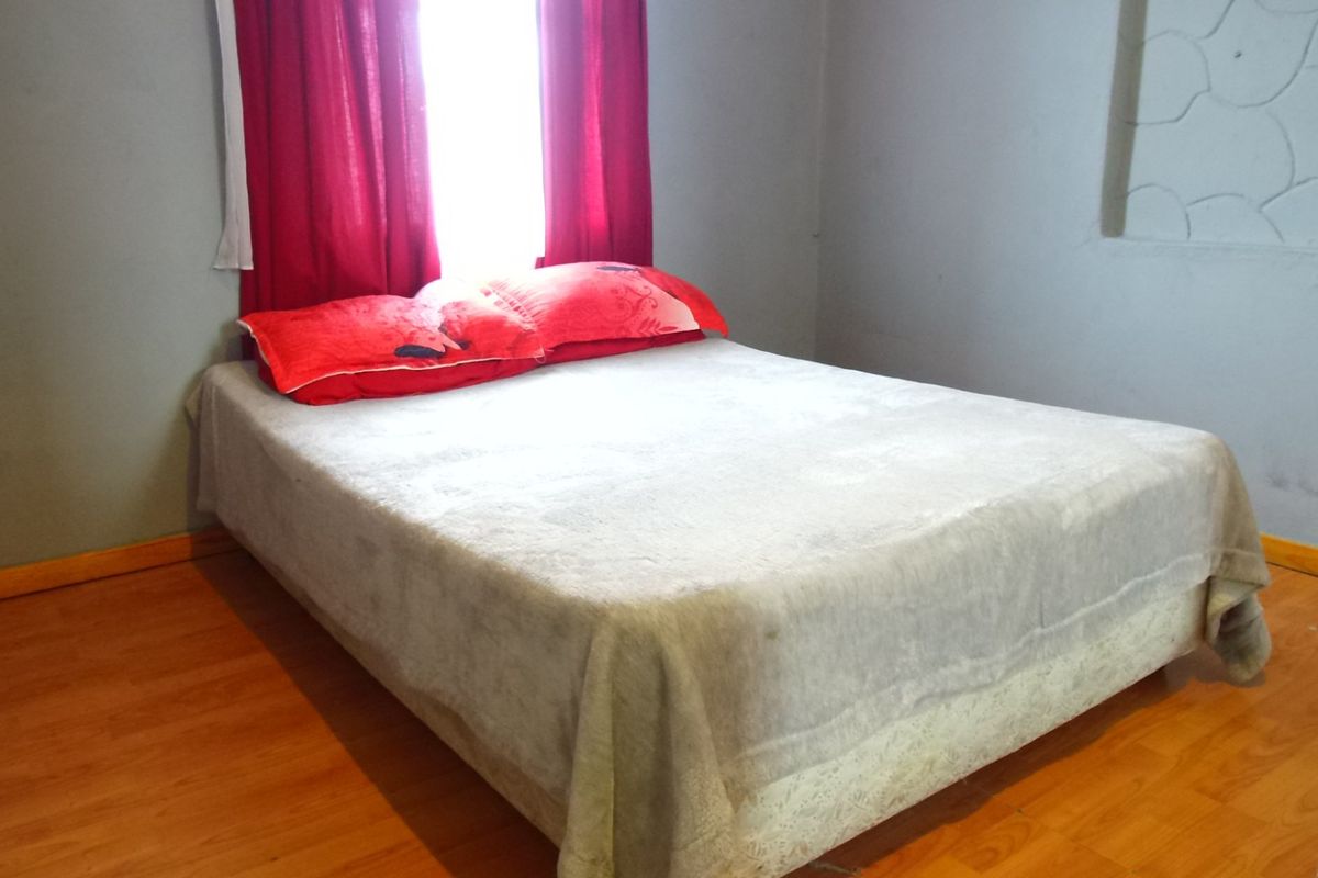 A bedroom featuring laminate flooring and a recessed wall detail, requiring minor cosmetic updates to improve the overall finish.
