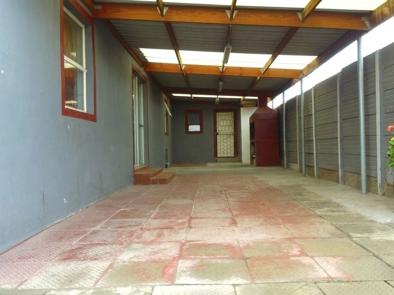 A covered outdoor patio area featuring tiled flooring, a built-in braai, and direct access to the home.