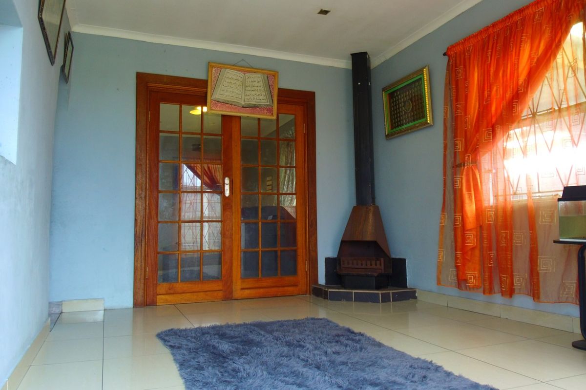 A living room featuring tiled flooring, a corner-mounted freestanding fireplace, and wooden French doors leading to an adjacent space.