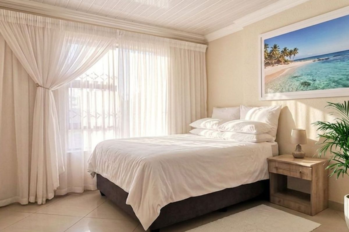 A well-lit bedroom featuring tiled flooring, a textured tongue and groove ceiling, and a large sliding door providing natural light.