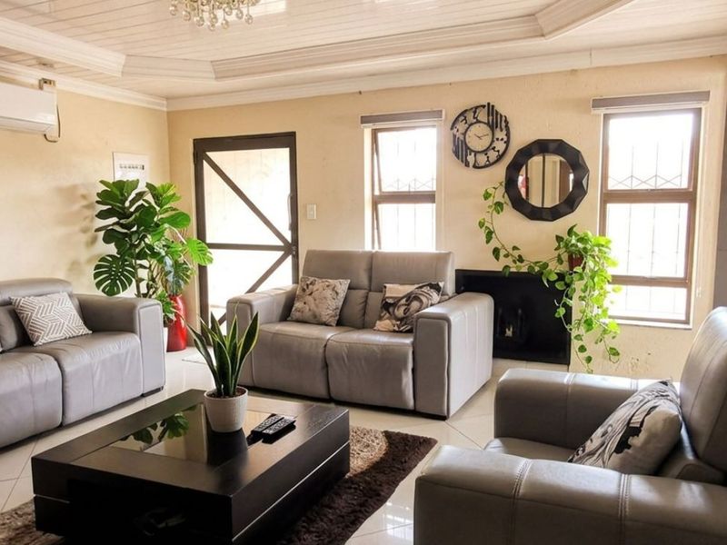 A comfortable living room featuring tiled flooring, a recessed ceiling, a built-in fireplace, and a wall-mounted air conditioning unit.