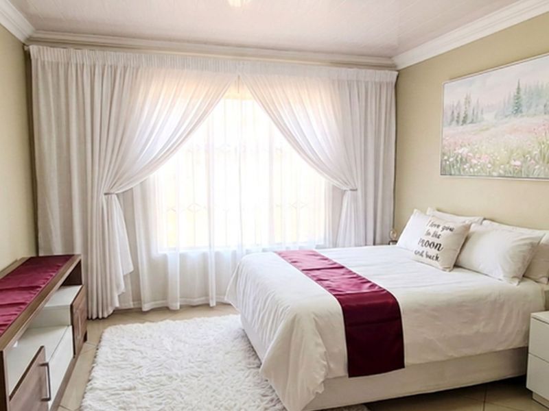 A well-maintained bedroom featuring neutral wall tones, crown molding, and tiled flooring, providing a comfortable and inviting living space.