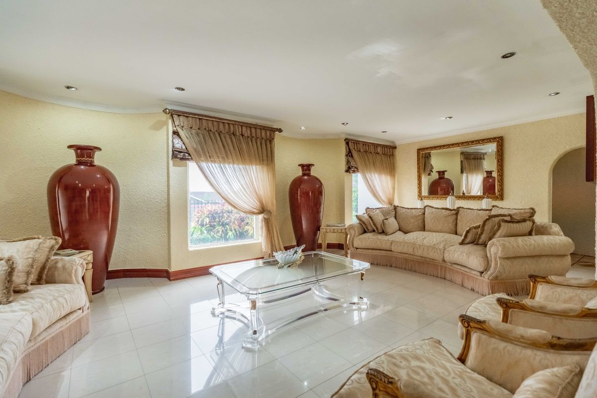 A spacious living room featuring tiled flooring, recessed downlights, and textured walls, offering a bright and comfortable area for relaxation.