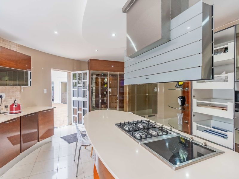 Modern kitchen featuring a curved island with integrated gas and electric cooktops, high-end cabinetry, and direct access to an outdoor area.