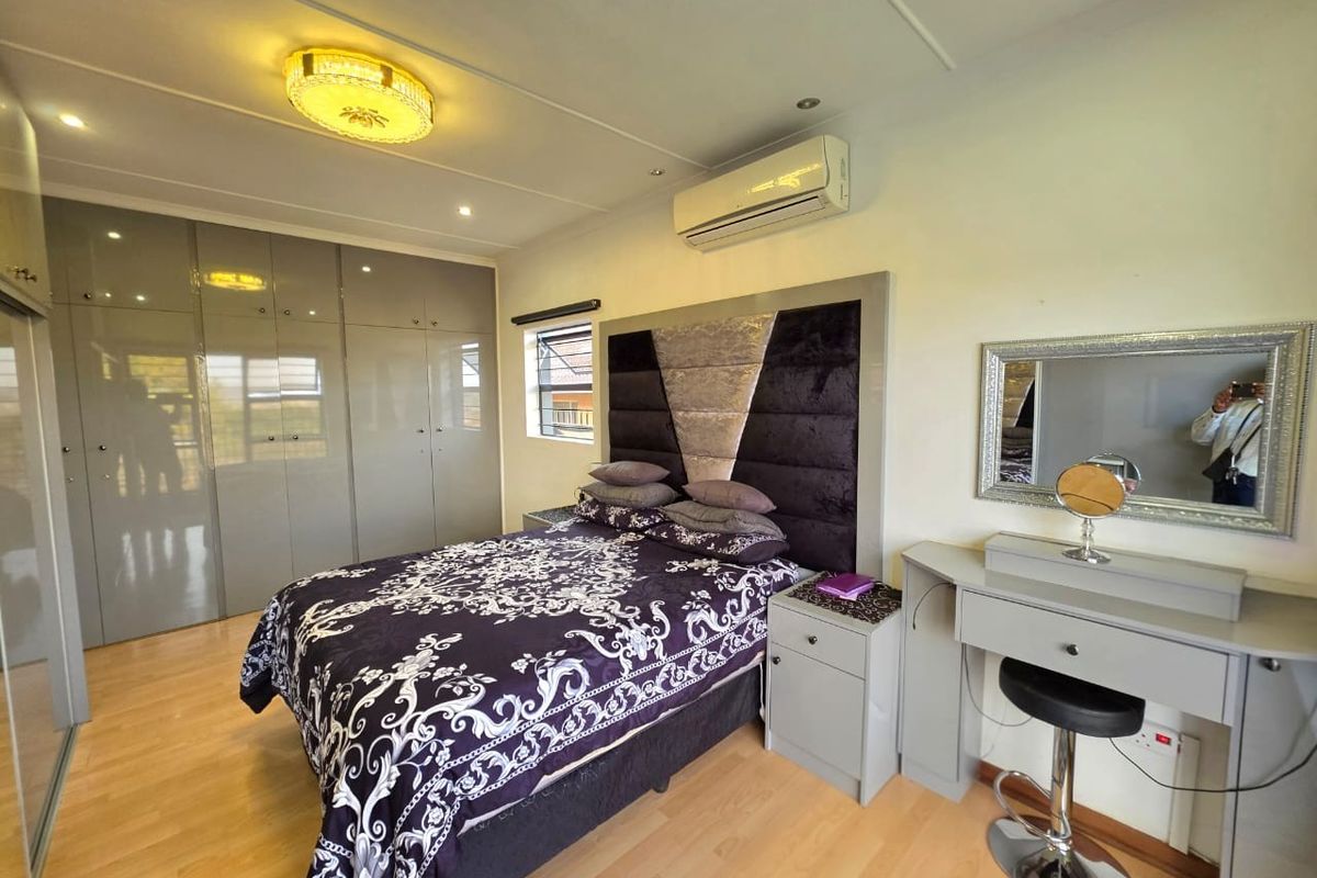A well-maintained bedroom featuring built-in cupboards, laminate flooring, and a split-system air conditioner for climate control.