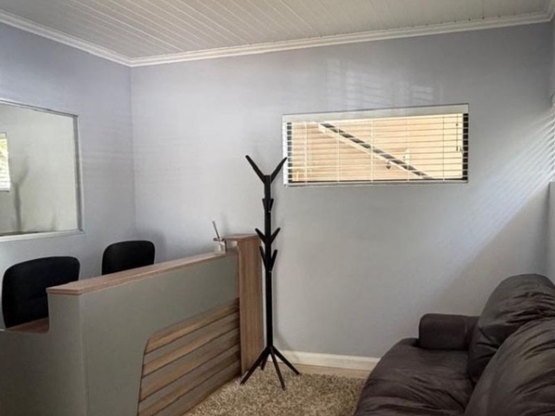 A functional office space featuring a built-in reception desk, neutral wall finishes, and venetian blinds providing natural light.