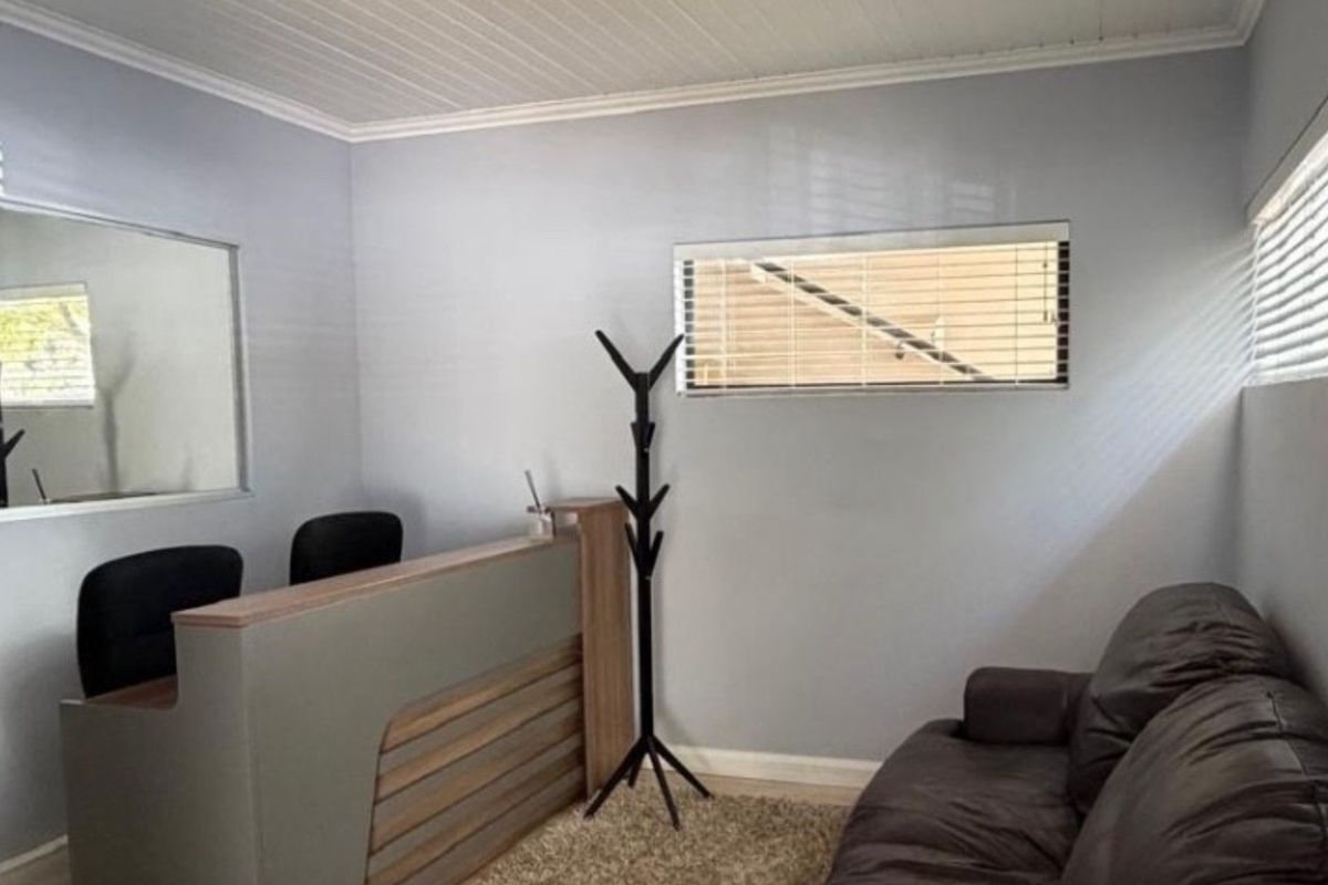 A functional office space featuring a built-in reception desk, neutral wall finishes, and venetian blinds providing natural light.
