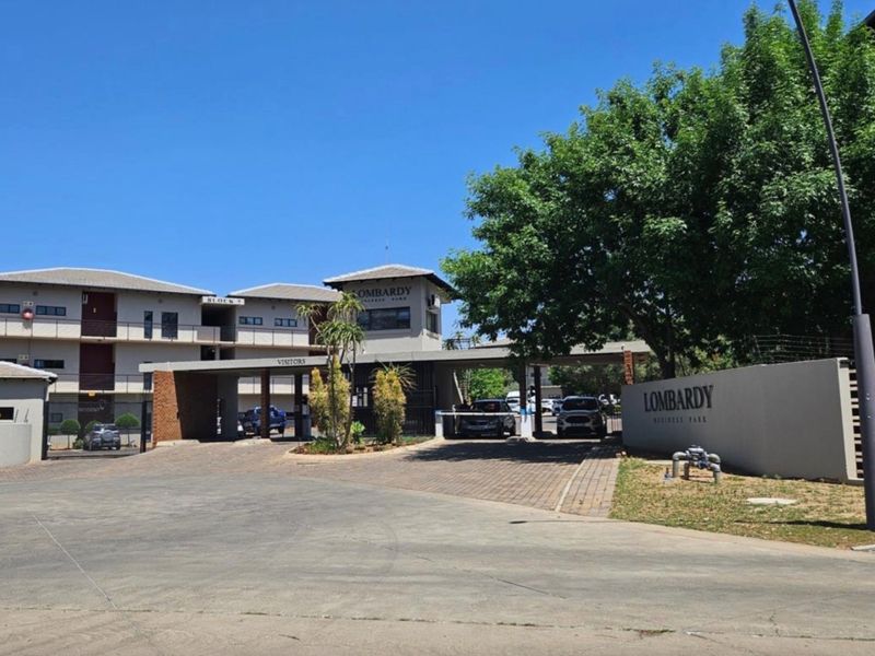 Front entrance view of Lombardy Business Park featuring a paved driveway, security boom gate, and professional signage.