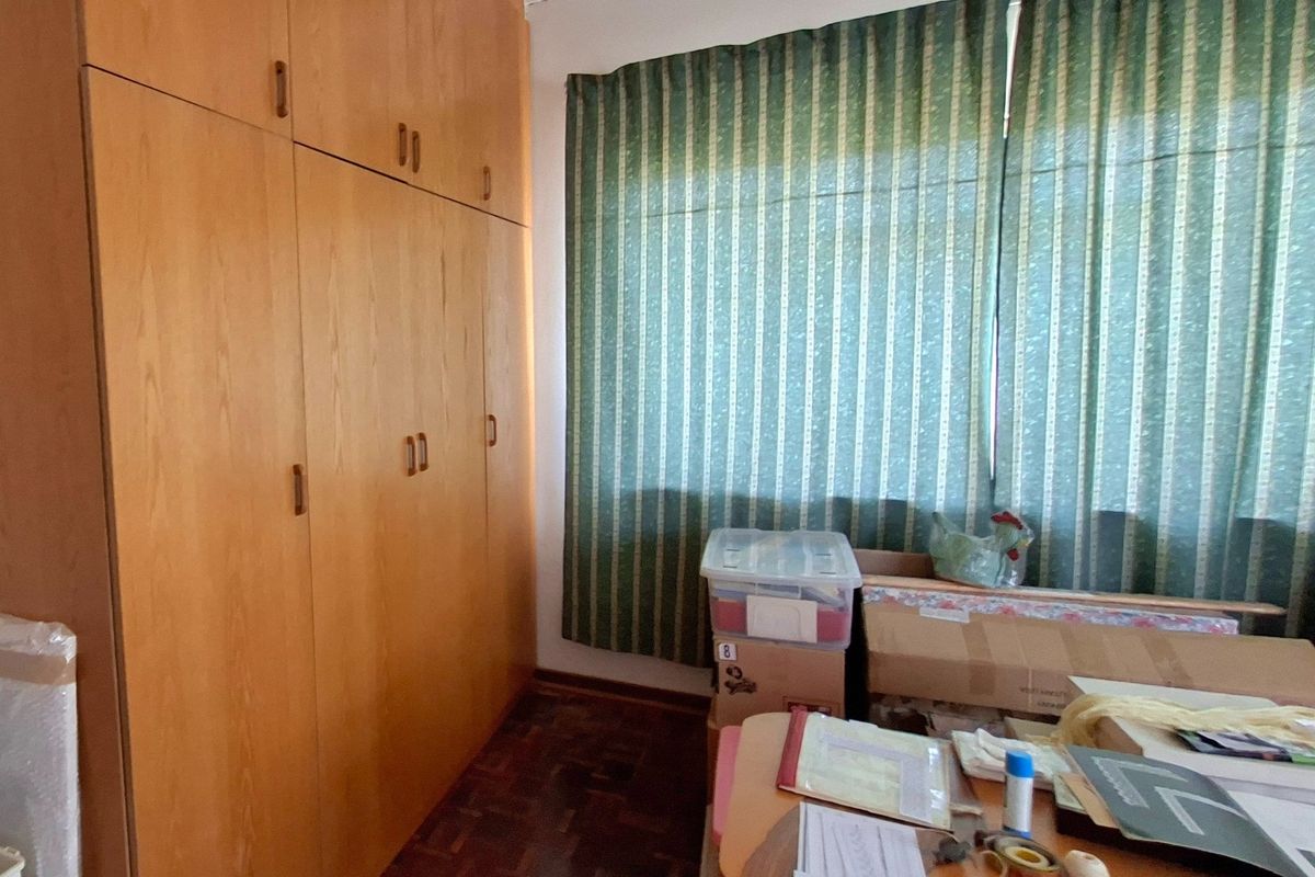 A bedroom featuring floor-to-ceiling built-in wooden cupboards and traditional parquet flooring, offering ample storage space.
