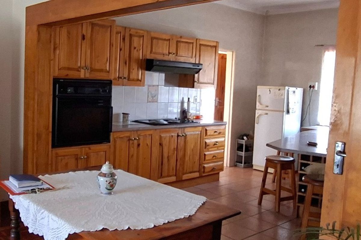 A functional kitchen featuring traditional wooden cabinetry, built-in oven, extractor fan, and tiled flooring, offering a classic layout with potential for modern updates.