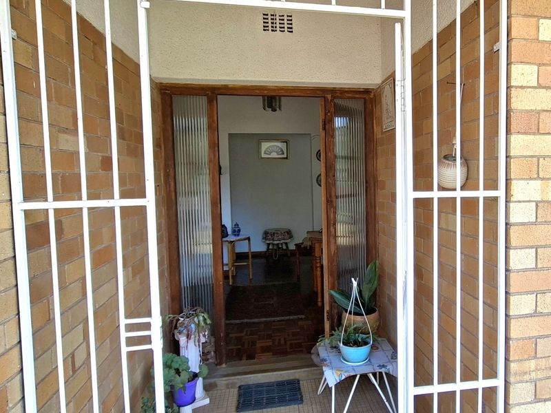 Entrance area featuring a white security gate, brick facade, and timber door frame with ribbed glass sidelights leading into the home.