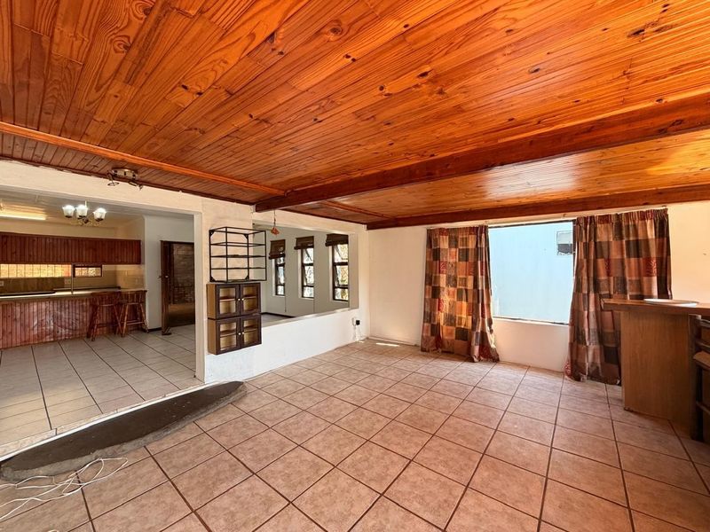 Spacious open-plan living area featuring a timber tongue and groove ceiling, ceramic tiled flooring, and a built-in bar counter.