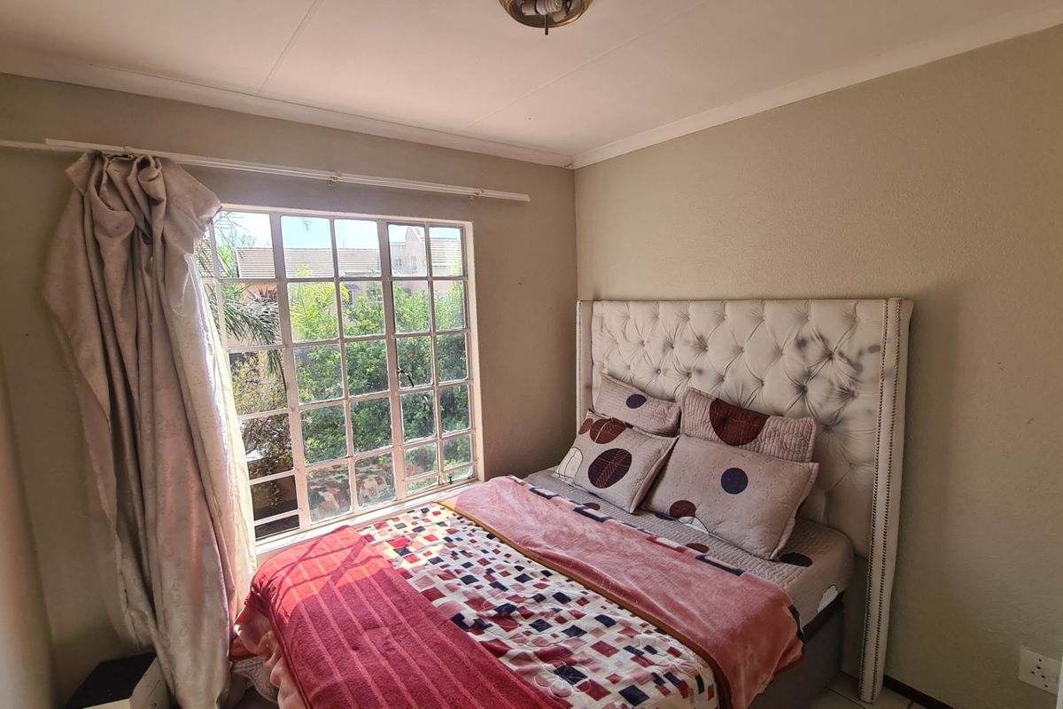 A bedroom featuring a grid-pane window providing natural light and a neutral wall finish.