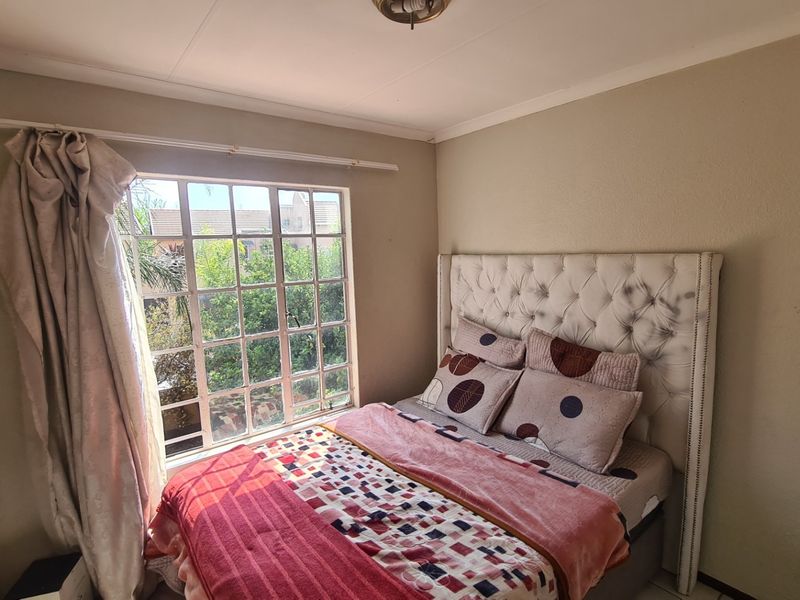 A bedroom featuring a grid-pane window providing natural light and a neutral wall finish.