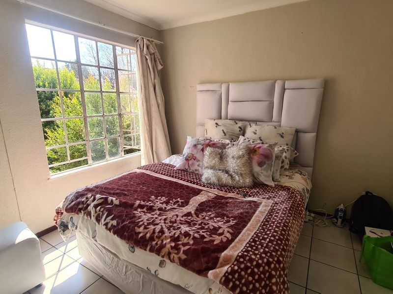 A bedroom featuring tiled flooring and a large window providing natural light, with neutral wall finishes.