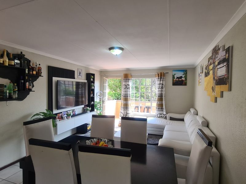 Open-plan living and dining area featuring tiled flooring, built-in media cabinetry, and direct access to an outdoor balcony through a sliding glass door.
