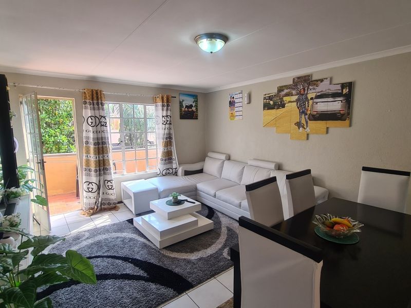 Open-plan living and dining area featuring tiled flooring and direct access to an outdoor balcony through a sliding door.