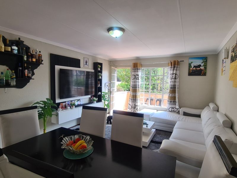 Open-plan living and dining area featuring a built-in media unit and direct access to an outdoor balcony through a sliding glass door.