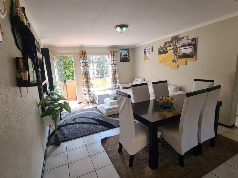 Open-plan living and dining area featuring tiled flooring and direct access to an outdoor balcony through a sliding glass door.
