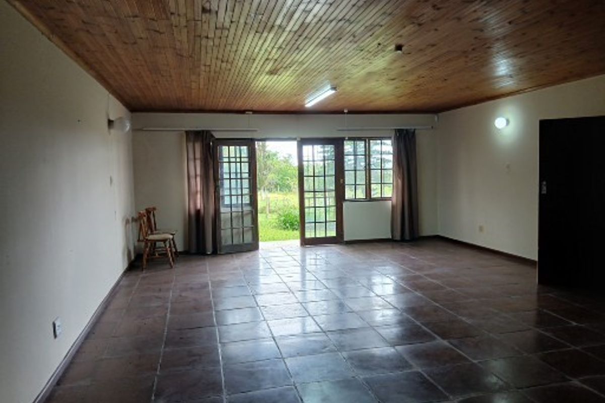 Spacious living area featuring a timber tongue and groove ceiling, tiled flooring, and direct access to the garden through double french doors.