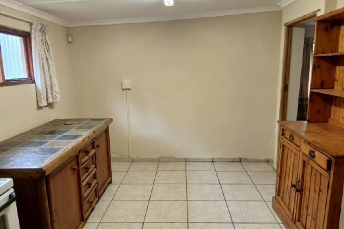 A functional kitchen area featuring tiled flooring, built-in wooden cabinetry with tiled countertops, and basic overhead lighting.