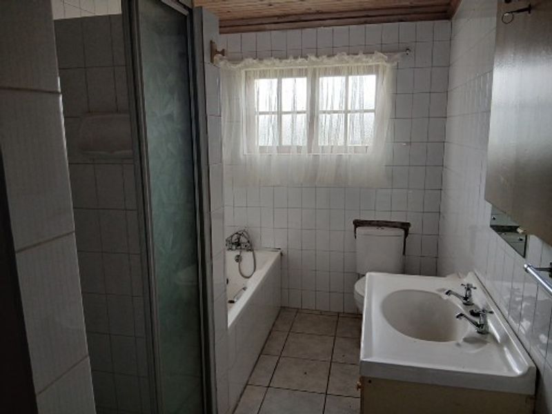 A dated bathroom featuring a shower enclosure, bathtub, toilet, and pedestal basin with tiled finishes and a timber ceiling.