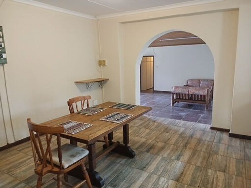 Dining area featuring tiled flooring and a classic architectural archway leading into an adjacent living space.